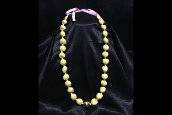 37 inch Natural Kukui Nut Lei featuring a 24K Gold Plated center Kukui Nut on a pink ribbon