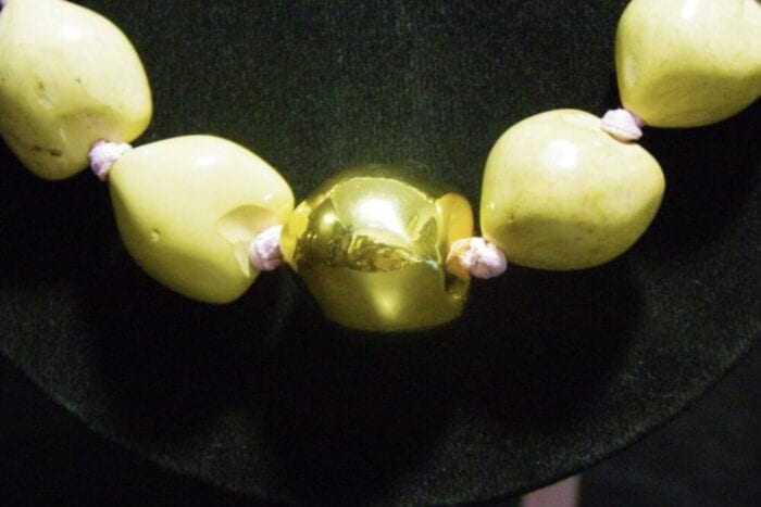 37 inch Natural Kukui Nut Lei featuring a 24K Gold Plated center Kukui Nut on a pink ribbon