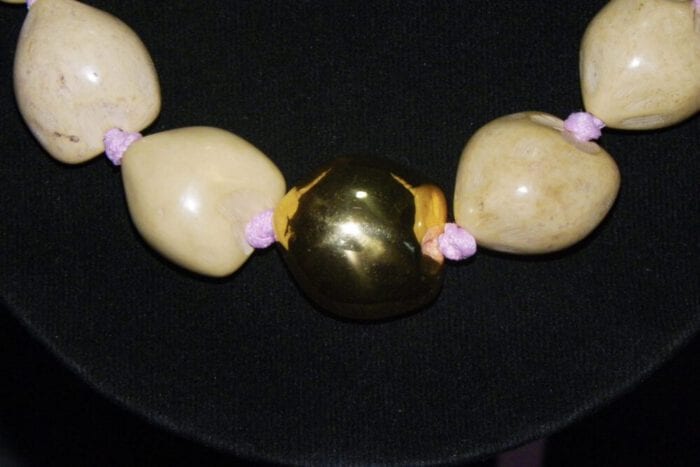 37 inch Natural Kukui Nut Lei featuring a 24K Gold Plated center Kukui Nut on a pink ribbon