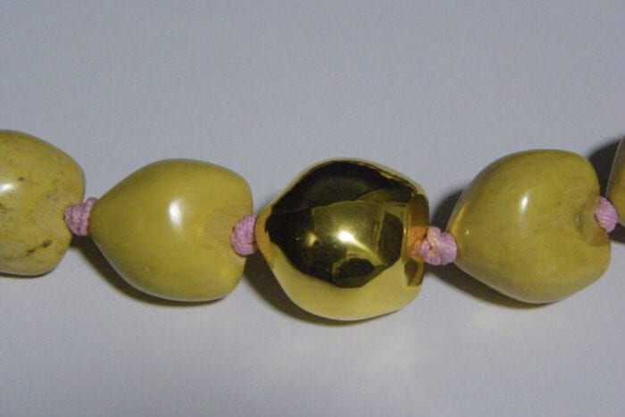 37 inch Natural Kukui Nut Lei featuring a 24K Gold Plated center Kukui Nut on a pink ribbon